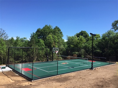 Outdoor multi-sport court with green flooring and white markings with two basketball hoops in Eau Claire.