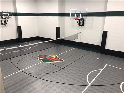 Indoor sports court with grey flooring and white markings, multiple basketball hoops and a net in the middle.