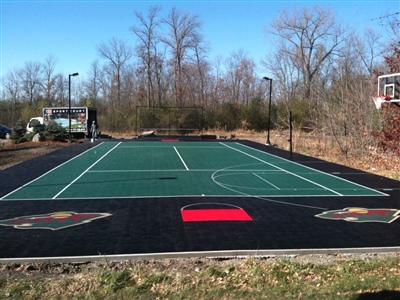 Outdoor multi-sport court with a green court and black boundary with multiple Minnesota Wild logos around the edges. 