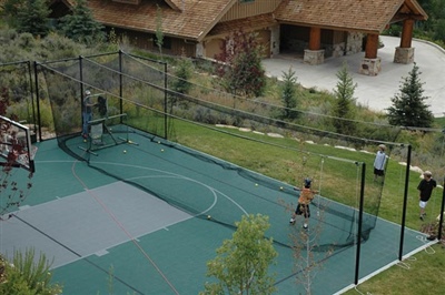 Outdoor batting practice area on multipurpose sport court with black netting.