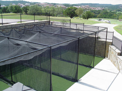 Multiple outdoor batting cages with faux turf and black netting in Shorewood.