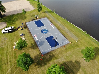  Outdoor sports court with a gray and blue surface, featuring two basketball hoops and the Minnesota Timberwolves central logo.