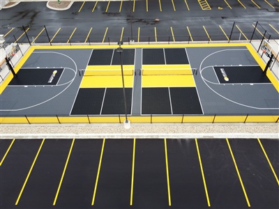 Outdoor sports court with a gray, black, and yellow surface, featuring two basketball courts and two tennis courts.