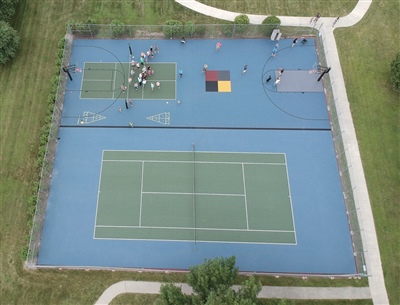  Outdoor sports complex with a blue and green surface, featuring a tennis court and a basketball court.