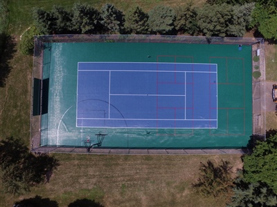 Outdoor sports court with a green and blue surface, featuring basketball hoops and tennis nets in Bayside.