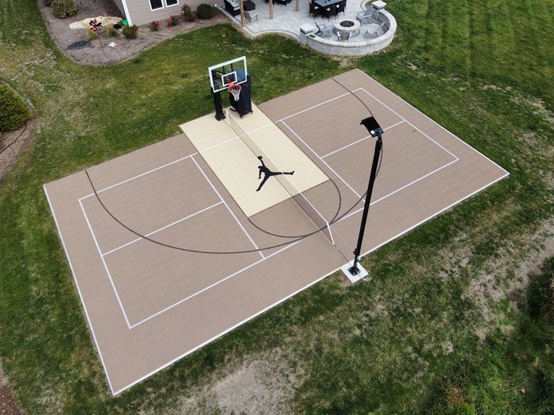 Aerial view of a completed 30x50 backyard basketball and multi-sport court with lighting in Menomonee Falls, WI